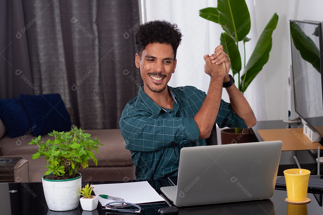 Jovem fazendo home office durante o dia na mesa com laptop