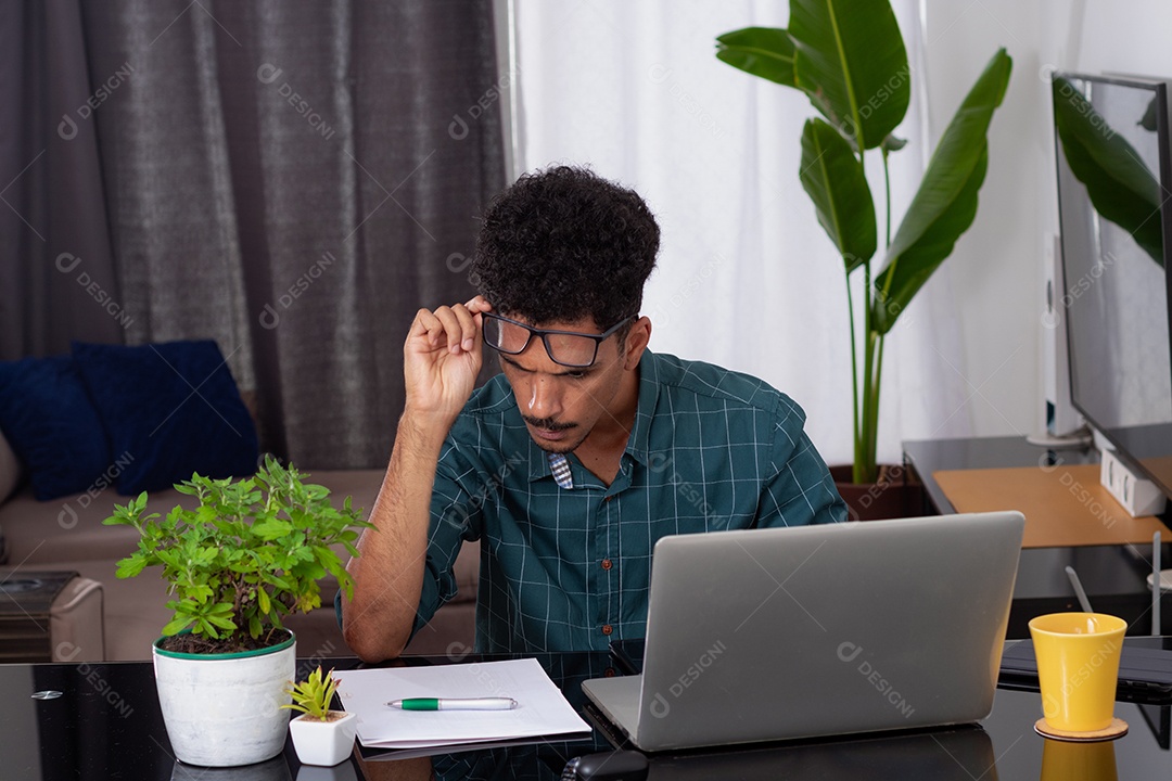 Jovem fazendo home office durante o dia na mesa com laptop