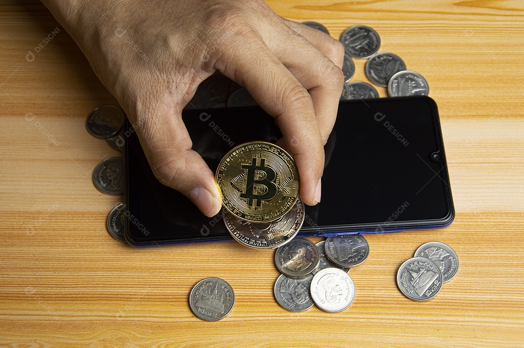 Moedas de ouro e Bitcoin colocadas no smartphone