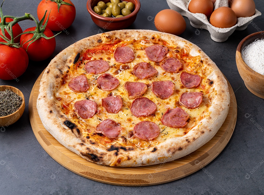 Pizza estilo linguiça calabresa sobre fundo de pedra com tomate, azeitonas e orégano.