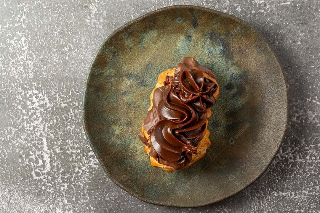 Bomba de chocolate ou éclair é uma padaria brasileira, sobremesa de comida doce, sobre mesa de mármore