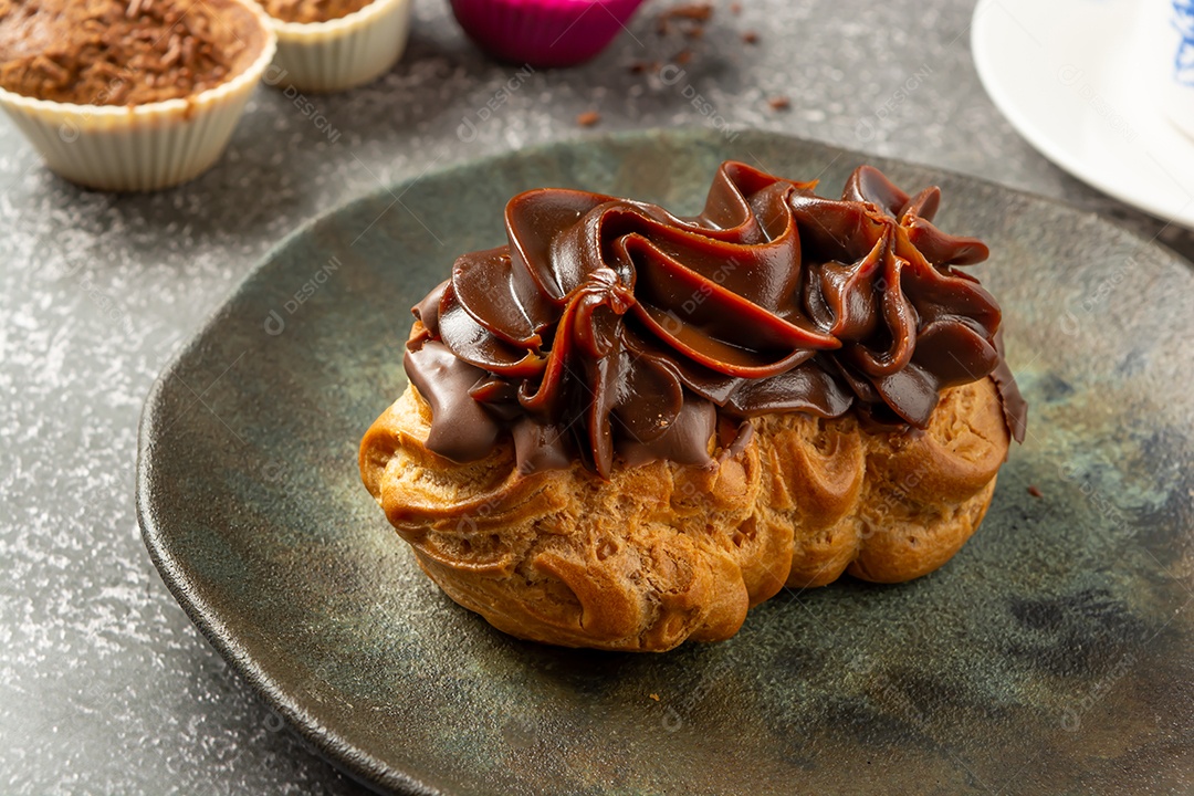 Bomba de chocolate ou éclair é uma padaria brasileira, sobremesa de comida doce, sobre mesa de mármore
