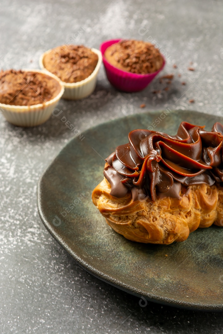 Bomba de chocolate ou éclair é uma padaria brasileira, sobremesa de comida doce, sobre mesa de mármore