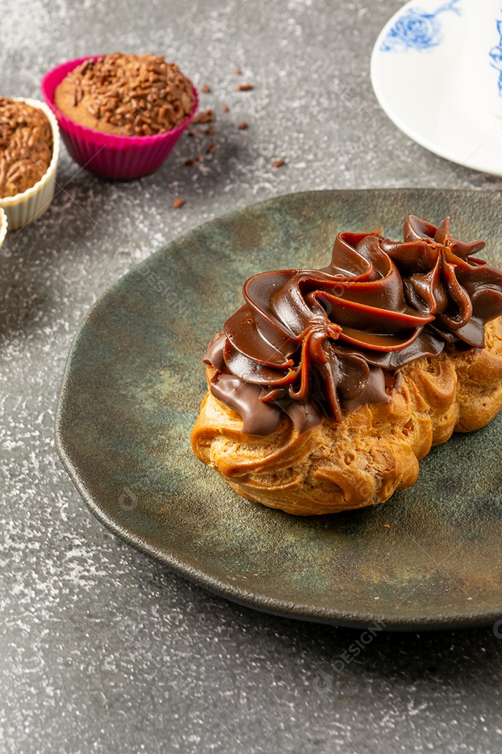 Bomba de chocolate ou éclair é uma padaria brasileira, sobremesa de comida doce, sobre mesa de mármore
