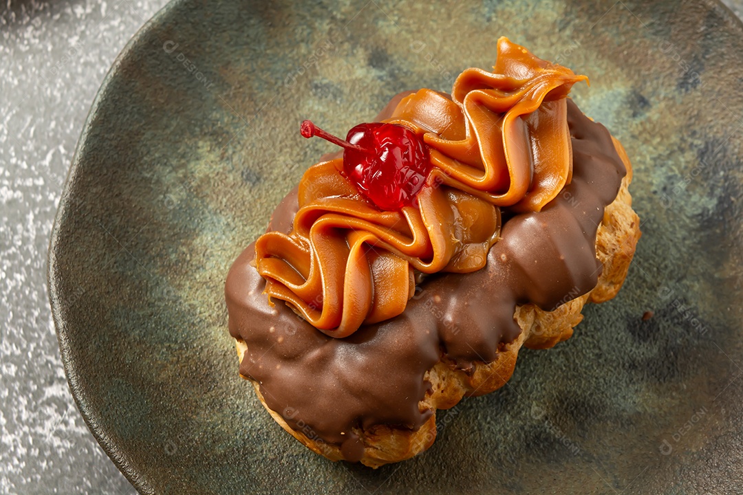 Bomba de chocolate ou éclair é uma padaria brasileira, sobremesa de comida doce, sobre mesa de mármore