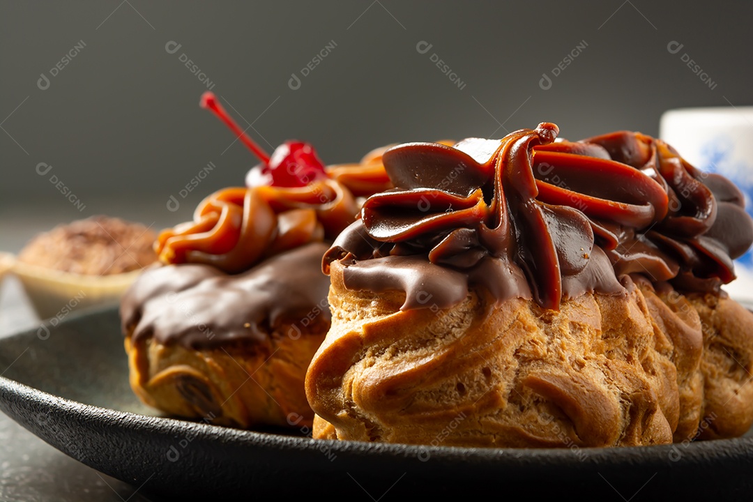 Bomba de chocolate ou éclair é uma padaria brasileira, sobremesa de comida doce, sobre mesa de mármore