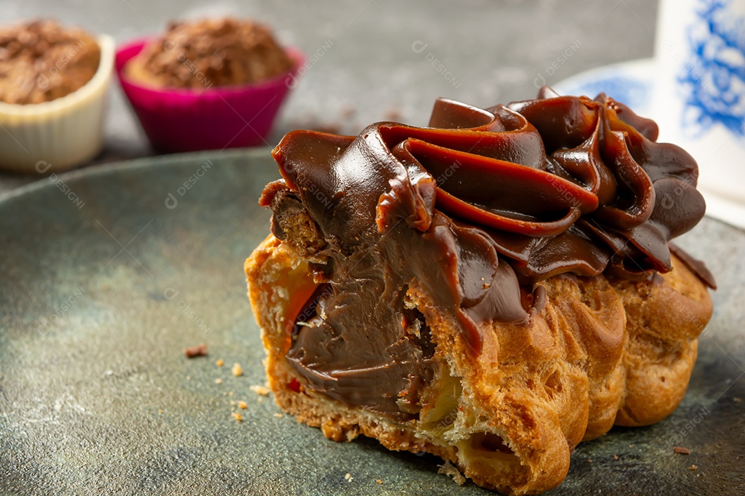 Bomba de chocolate ou éclair é uma padaria brasileira, sobremesa de comida doce, sobre mesa de mármore
