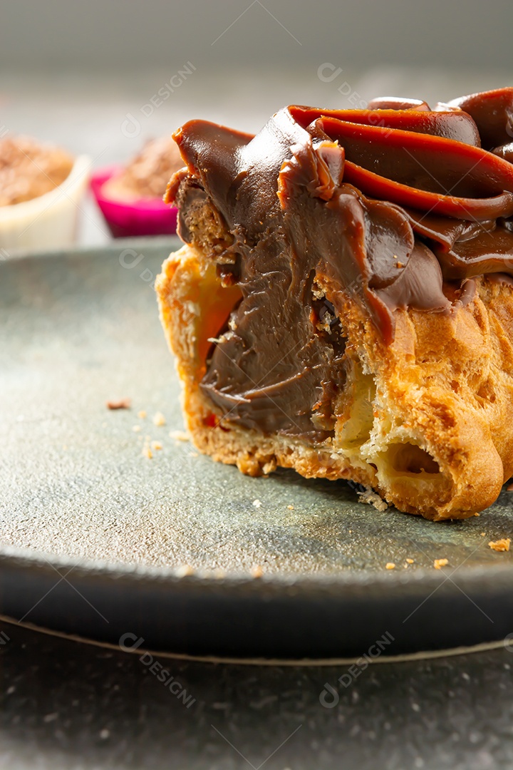 Bomba de chocolate ou éclair é uma padaria brasileira, sobremesa de comida doce, sobre mesa de mármore