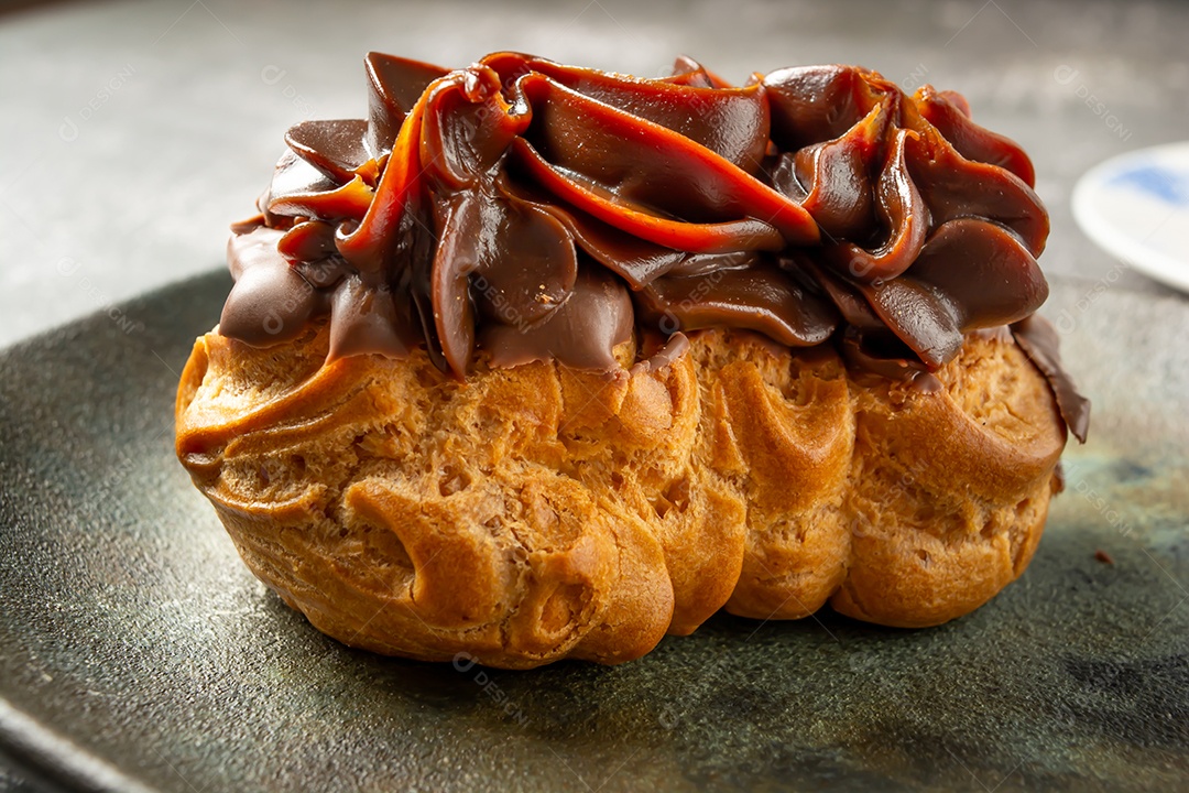 Bomba de chocolate ou éclair é uma padaria brasileira, sobremesa de comida doce, sobre mesa de mármore