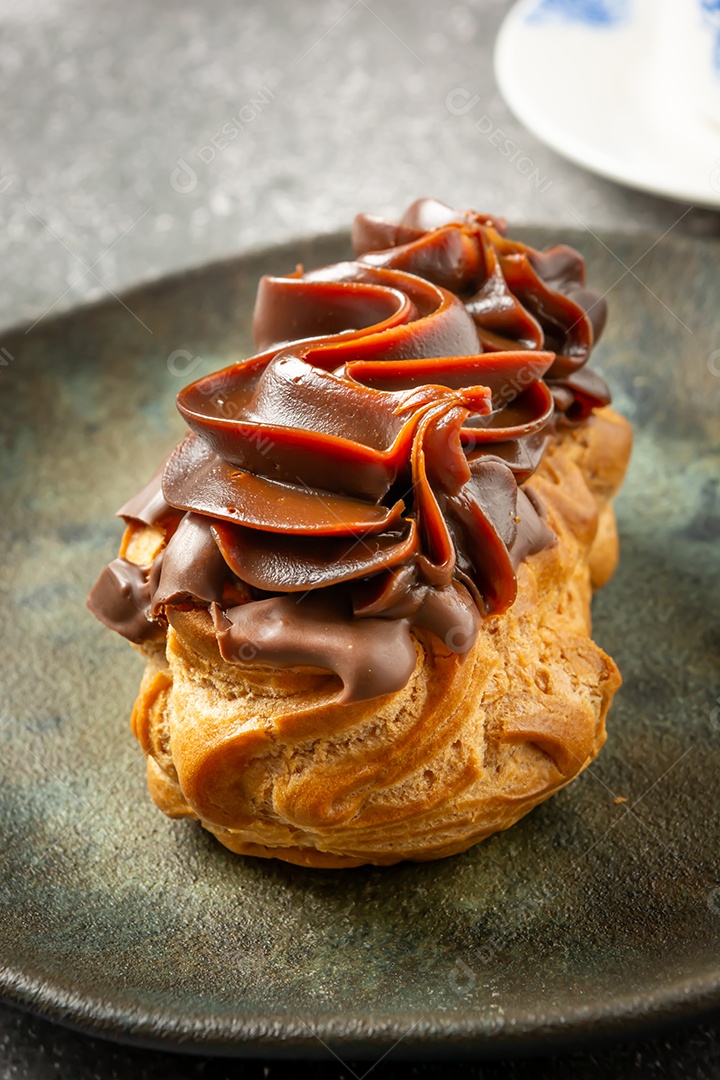 Bomba de chocolate ou éclair é uma padaria brasileira, sobremesa de comida doce, sobre mesa de mármore