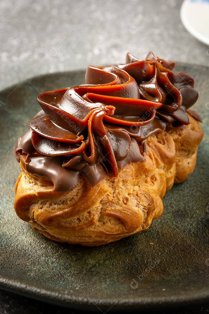 Bomba de chocolate ou éclair é uma padaria brasileira, sobremesa de comida doce, sobre mesa de mármore