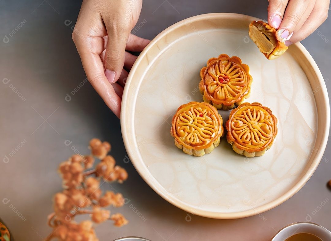 Mãos de pessoas comendo saborosos bolos redondos de lua no festival do meio do outono