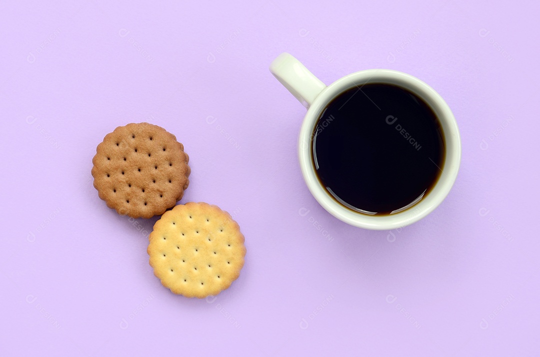 Composição plana da pausa para o café com biscoitos sanduíche marrons. Xícara de café quente branca e sobremesa marrom sobre um fundo lilás pastel da moda