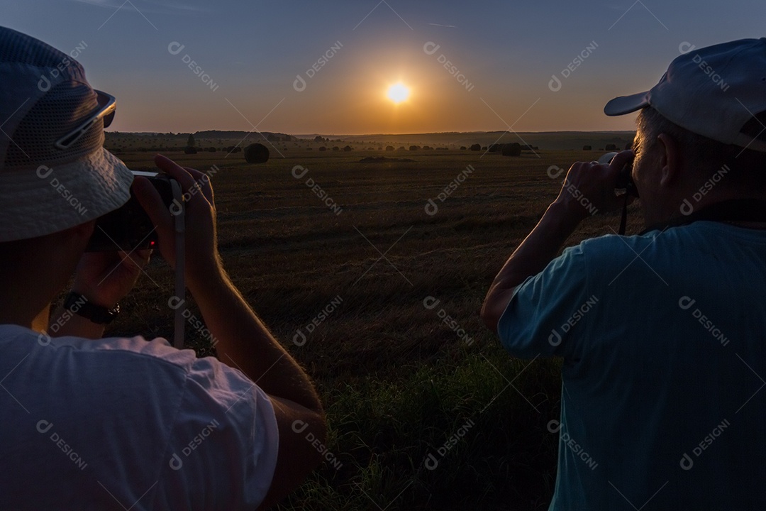 Dois fotógrafos fotografando o amanhecer em campo