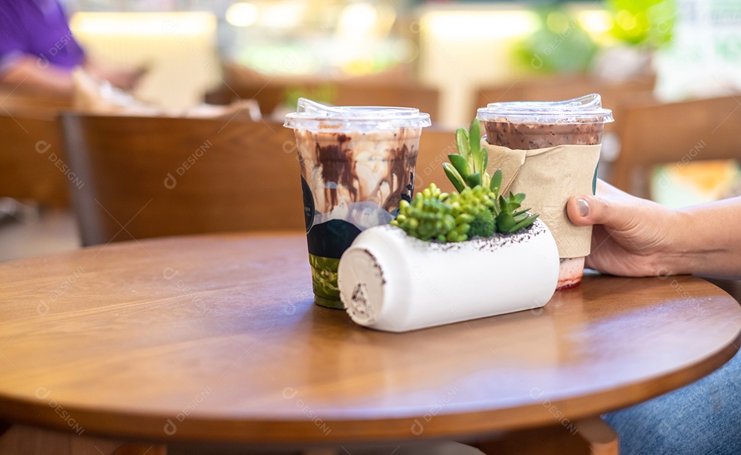Entregue mulheres segurando uma xícara de café na mesa de madeira na cafeteria