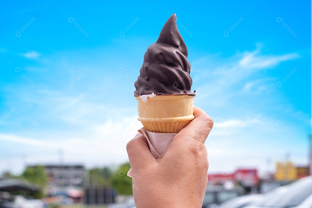 Casquinha de sorvete de creme de leite com chocolate macio serve em dia quente de verão em desfoque suave com fundo de céu azul