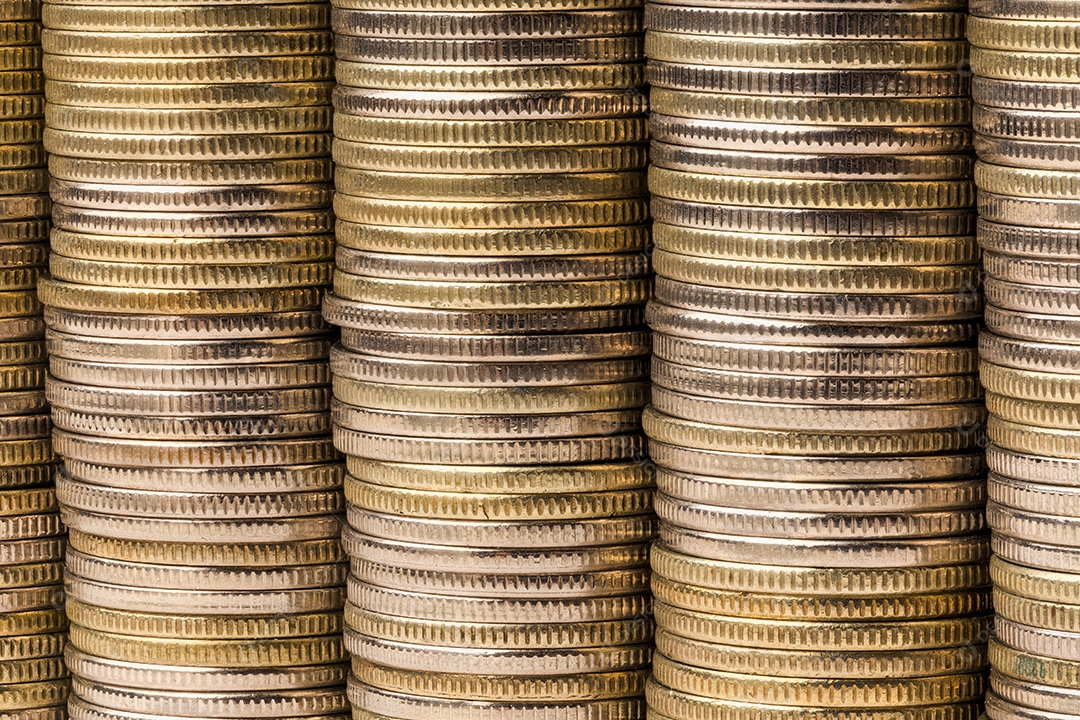 Cinco pilhas iguais de moedas fundidas em um fundo macro de parede sólida.