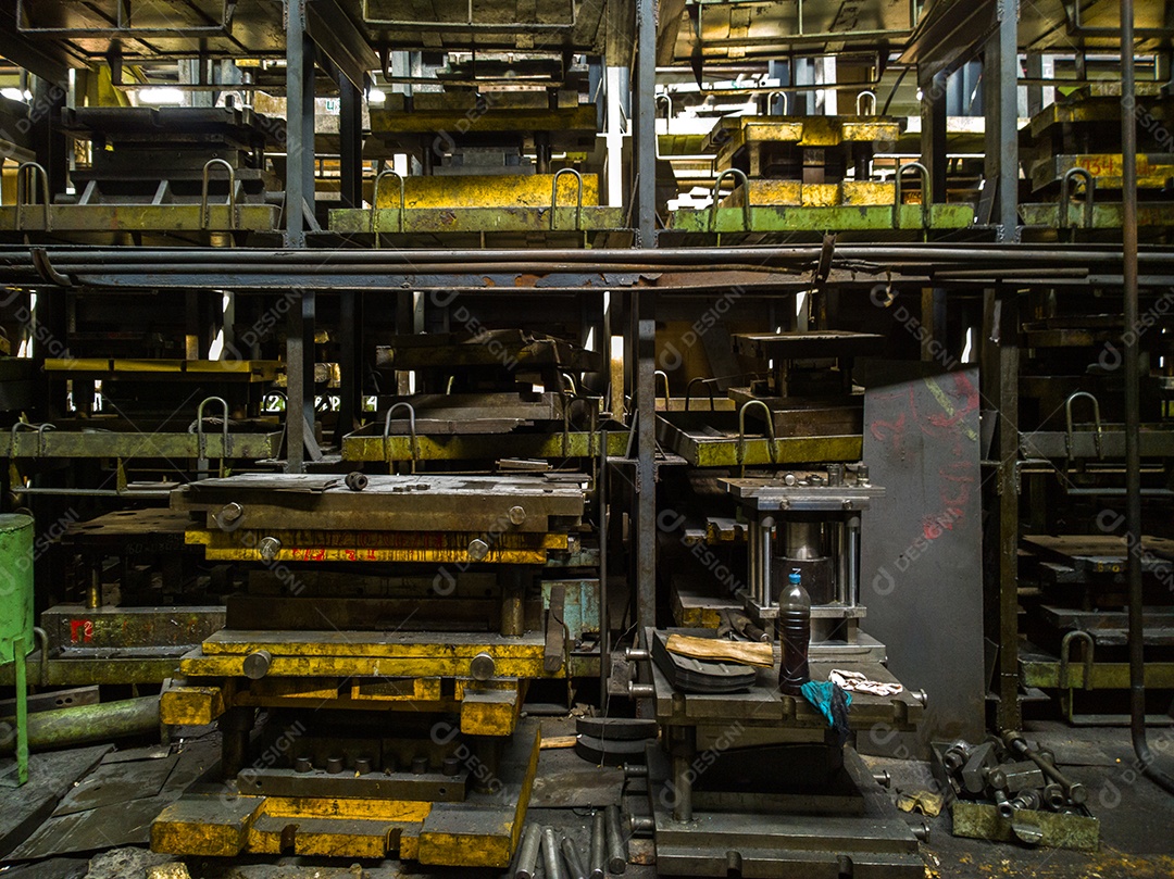 Oficina de carimbos bagunçada com grande suporte para carimbos dentro de uma fábrica de metalurgia