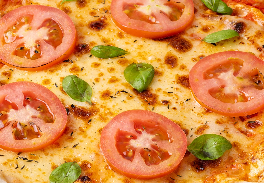 Closeup de pizza margherita com tomate e manjericão.