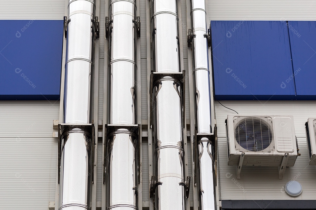 Tubos de ventilação cromados na parede externa do edifício industrial branco e azul