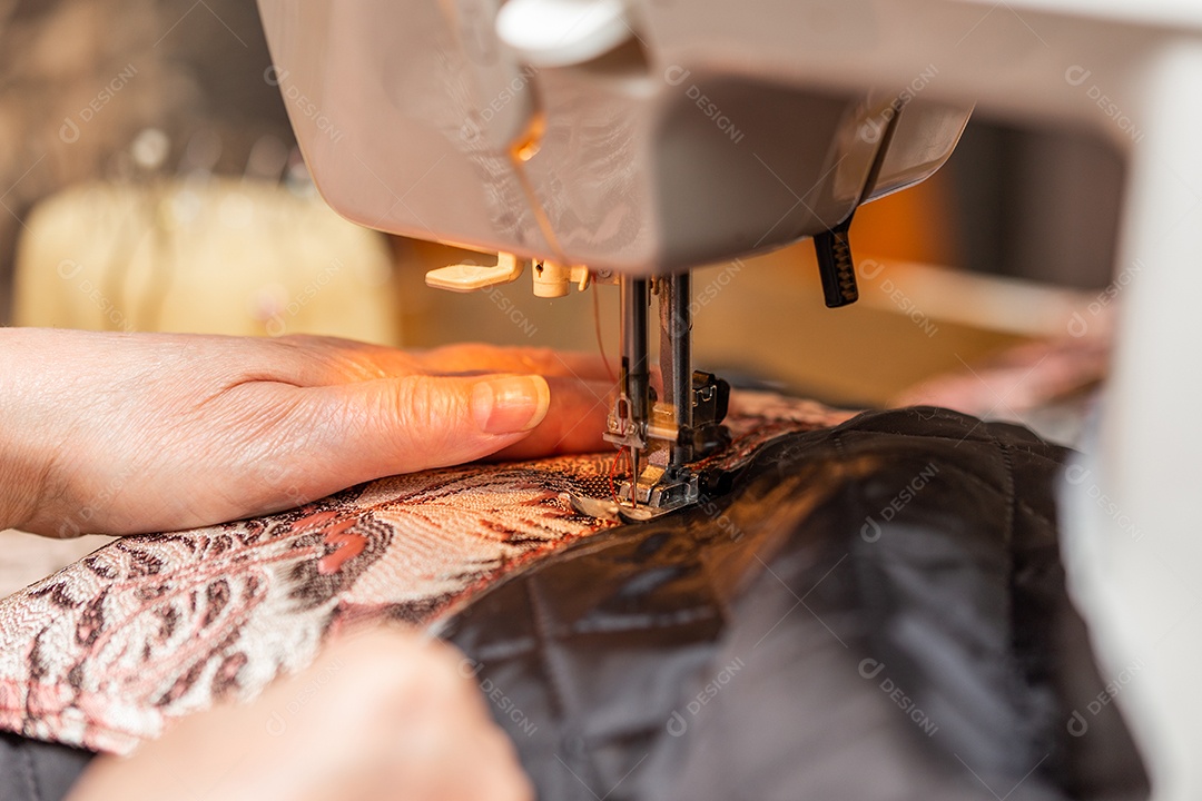 Uma visão de perto do processo de costura mão de uma senhora idosa usando máquina de costura