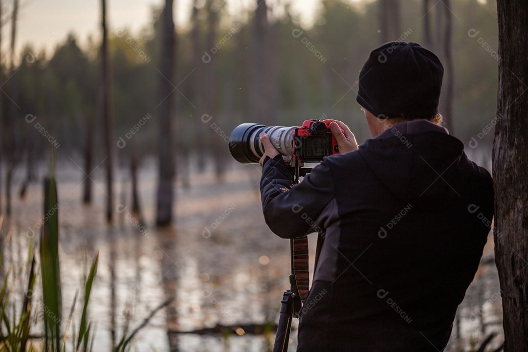 Câmera digital preta em tripé fotografando a paisagem matinal de neblina no lago de outono com foco seletivo