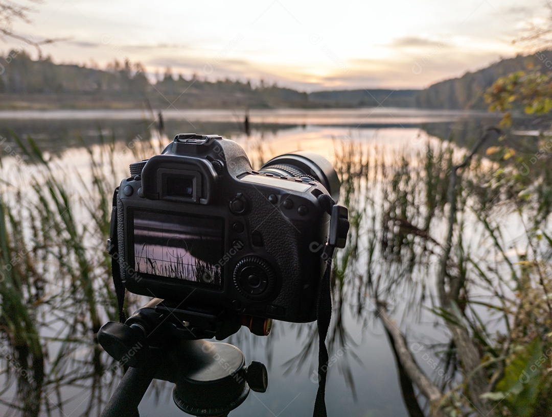 Câmera digital preta em tripé fotografando a paisagem matinal de neblina no lago de outono com foco seletivo