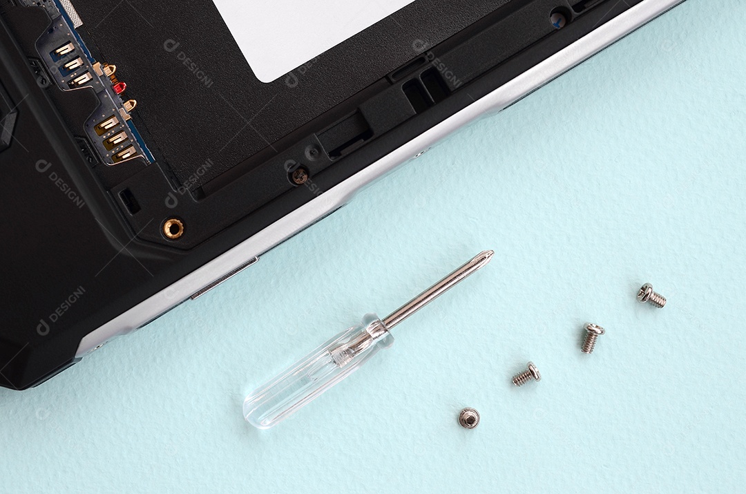 Uma pequena chave de fenda e alguns parafusos sobre um fundo azul