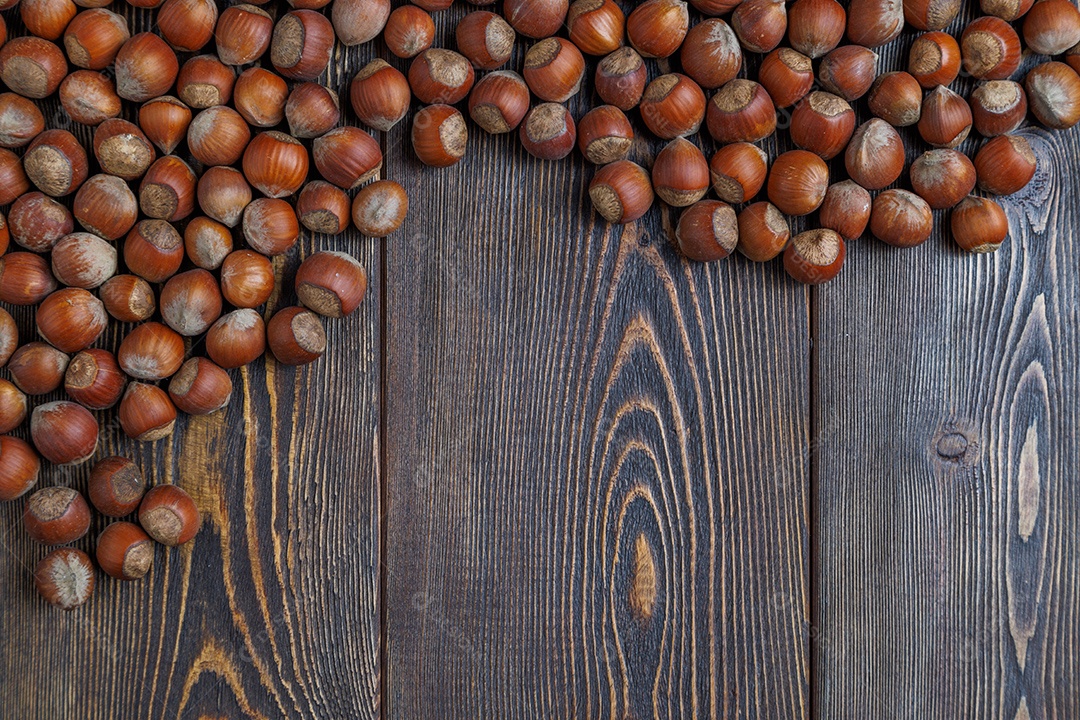 Avelãs com cascas dispostas sobre uma superfície de mesa de madeira marrom