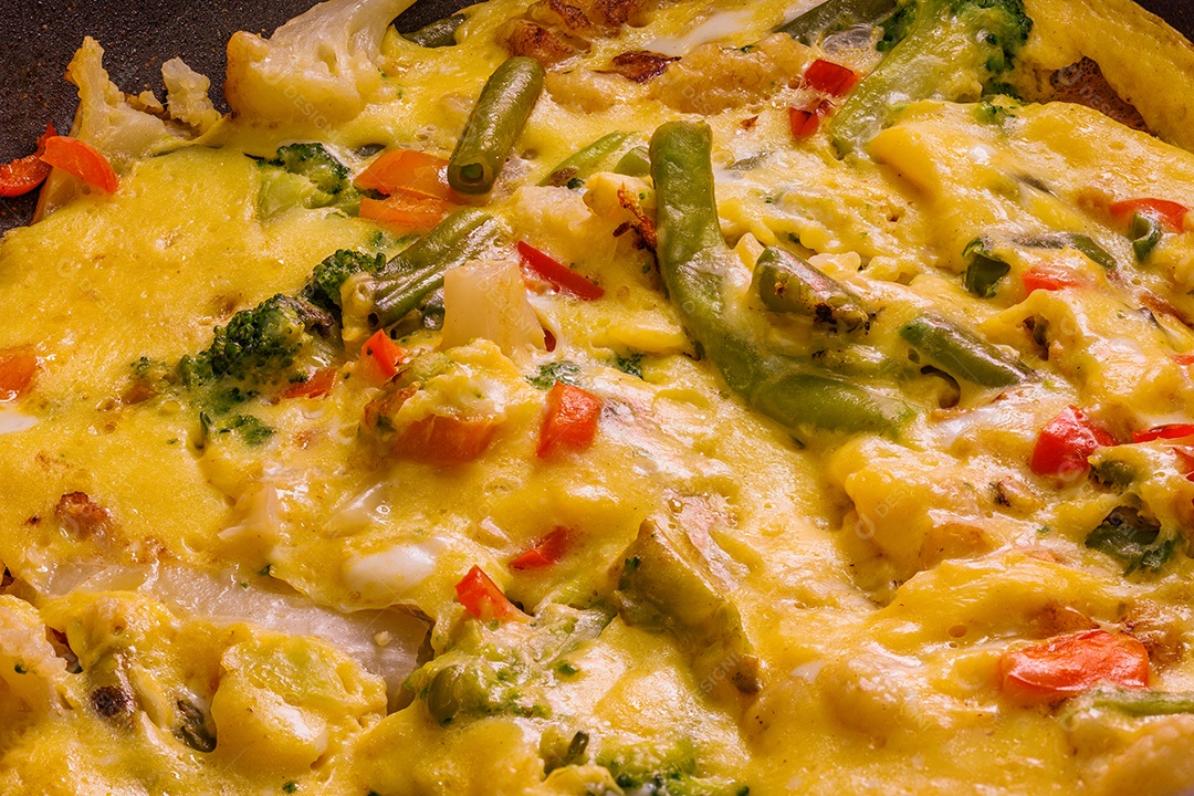 Prato com fatias de omelete de ovos mexidos com legumes e espátula de aço inoxidável