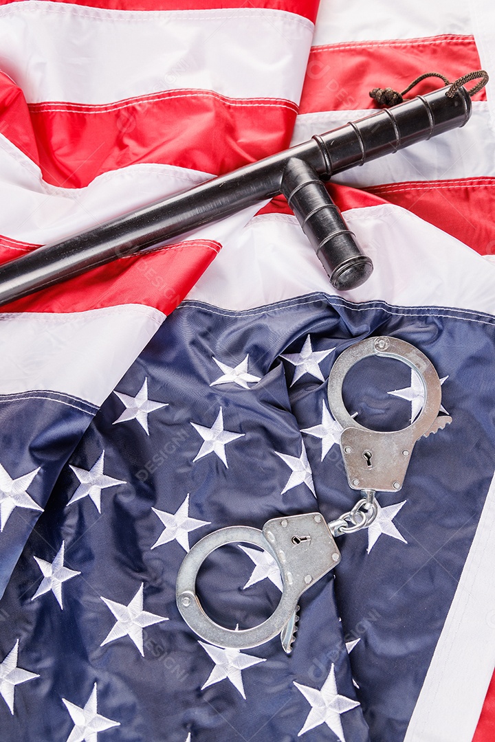 Algemas de metal prateado e cassetete de polícia perto da bandeira dos EUA em superfície de madeira