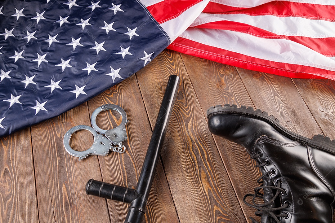 Algemas de metal prateado e cassetete de polícia perto da bandeira dos EUA em superfície de madeira