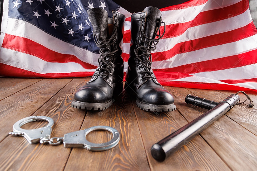 Algemas de metal prateado e cassetete de polícia perto da bandeira dos EUA em superfície de madeira