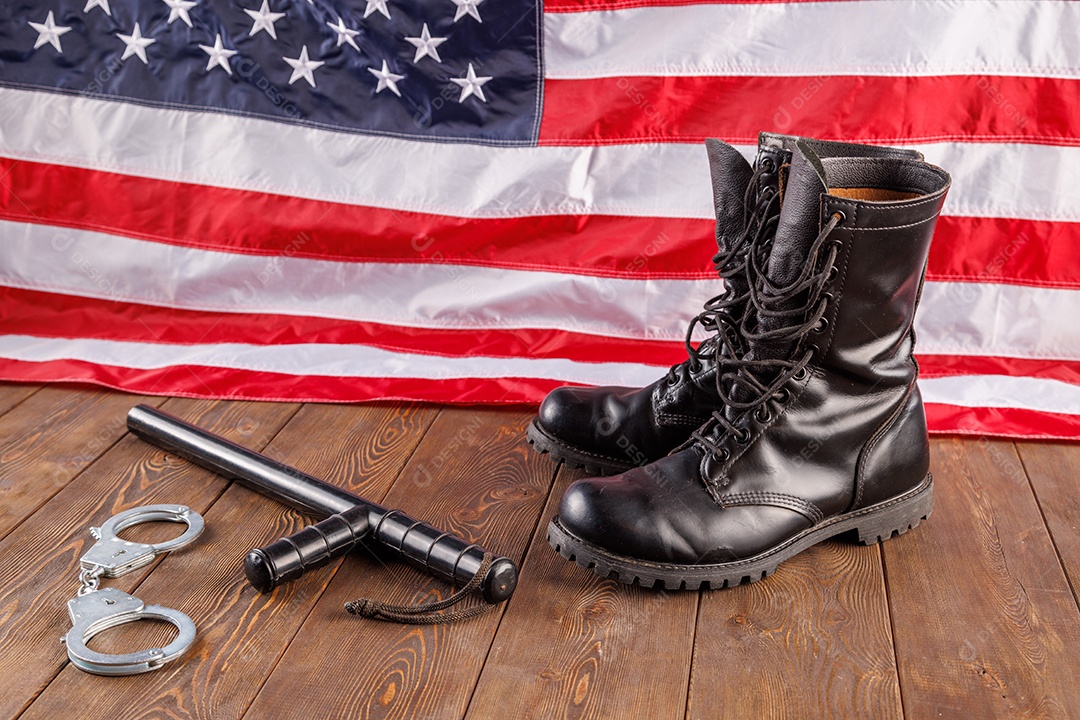 Algemas de metal prateado e cassetete de polícia perto da bandeira dos EUA em superfície de madeira