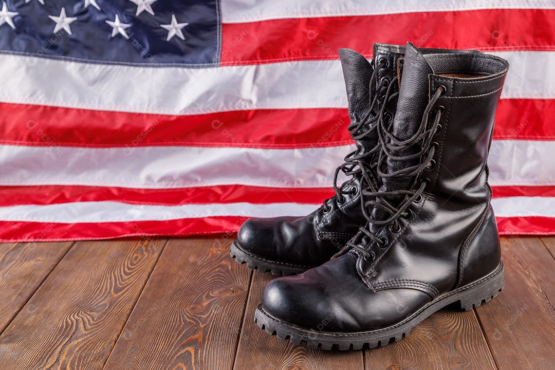 Botas pretas de cano curto em frente à bandeira dos EUA em superfície de madeira
