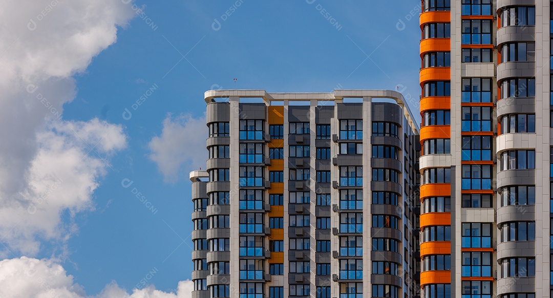Prédios de apartamentos altos recém-construídos em fundo de céu azul com nuvens brancas