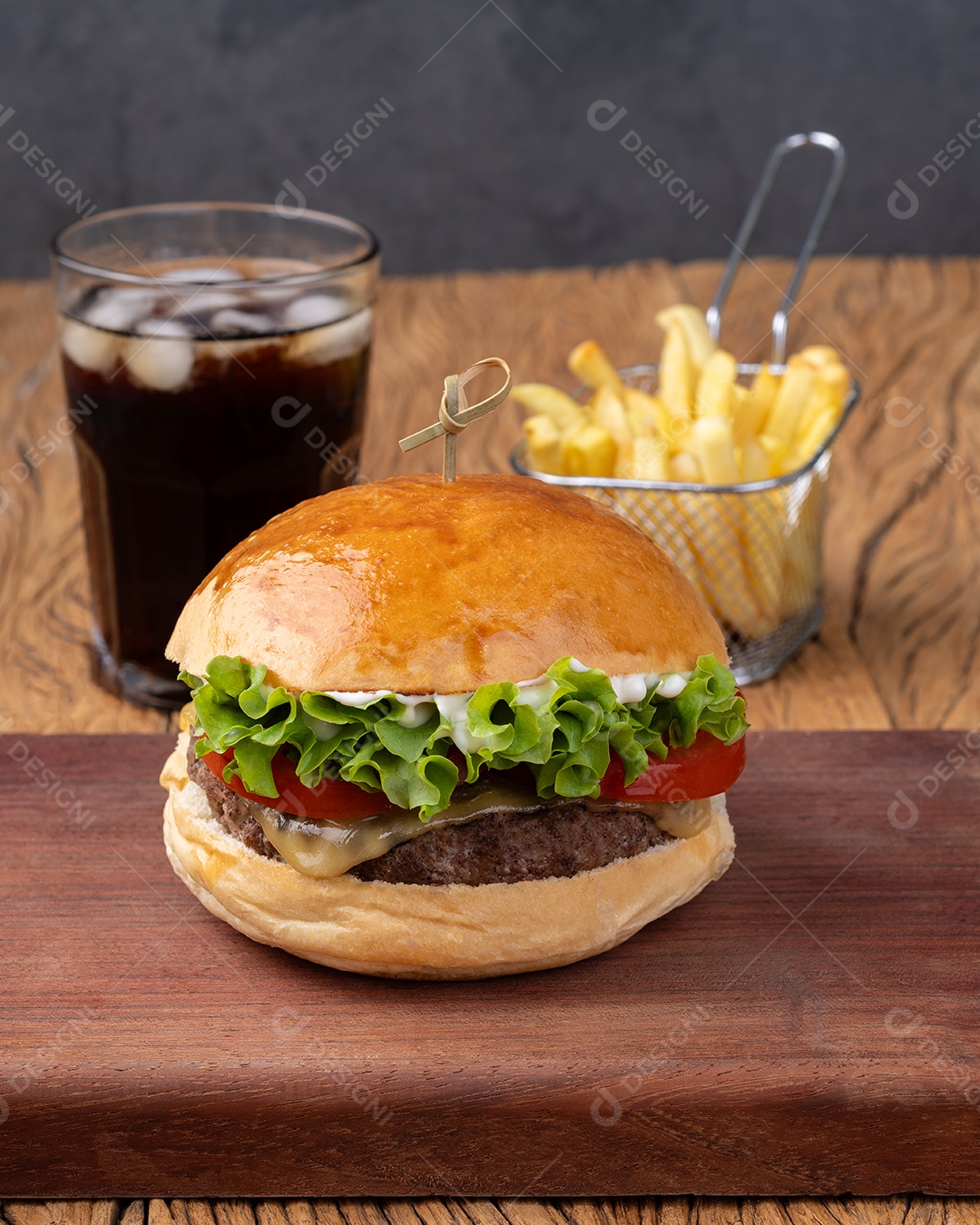 Cheeseburger com alface, tomate e maionese em tábua de madeira com batata frita e refrigerante.