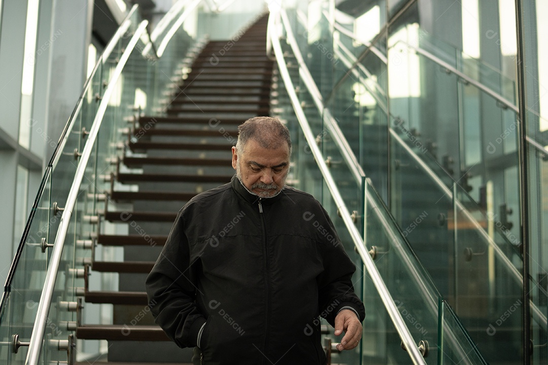 Homens adultos e idosos em pé na escada de um prédio com corrimão.