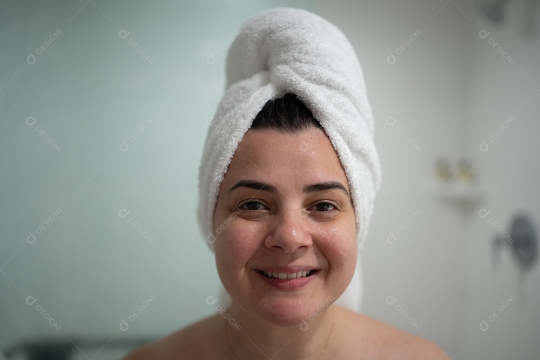 Mulher alegre no banheiro limpo, sorrindo, com toalha, irradiando felicidade e bem-estar.