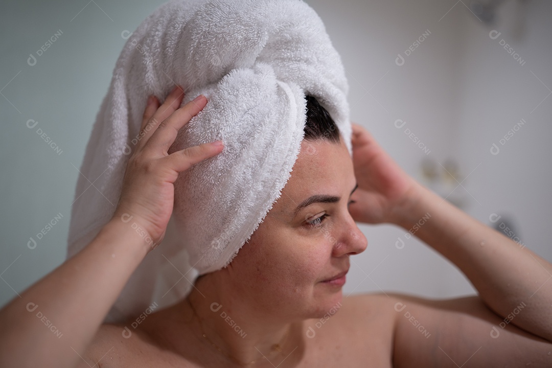 Mulher alegre no banheiro limpo, sorrindo, com toalha, irradiando felicidade e bem-estar.