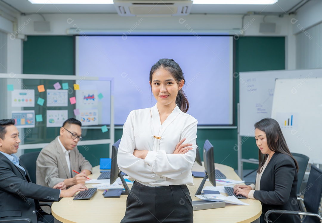 Retrato sorridente de uma mulher de negócios moderna em pé em um escritório em uma reunião de equipe.