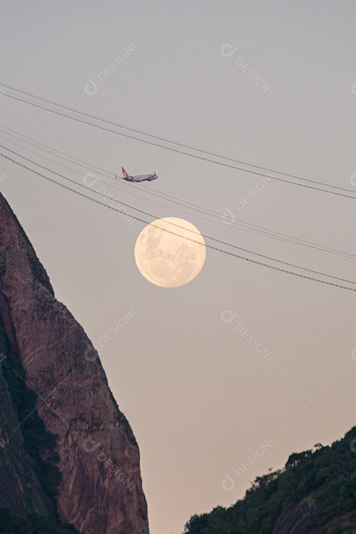 Nascer da lua atrás do Pão de Açúcar e avião passando de fundo no Rio de Janeiro