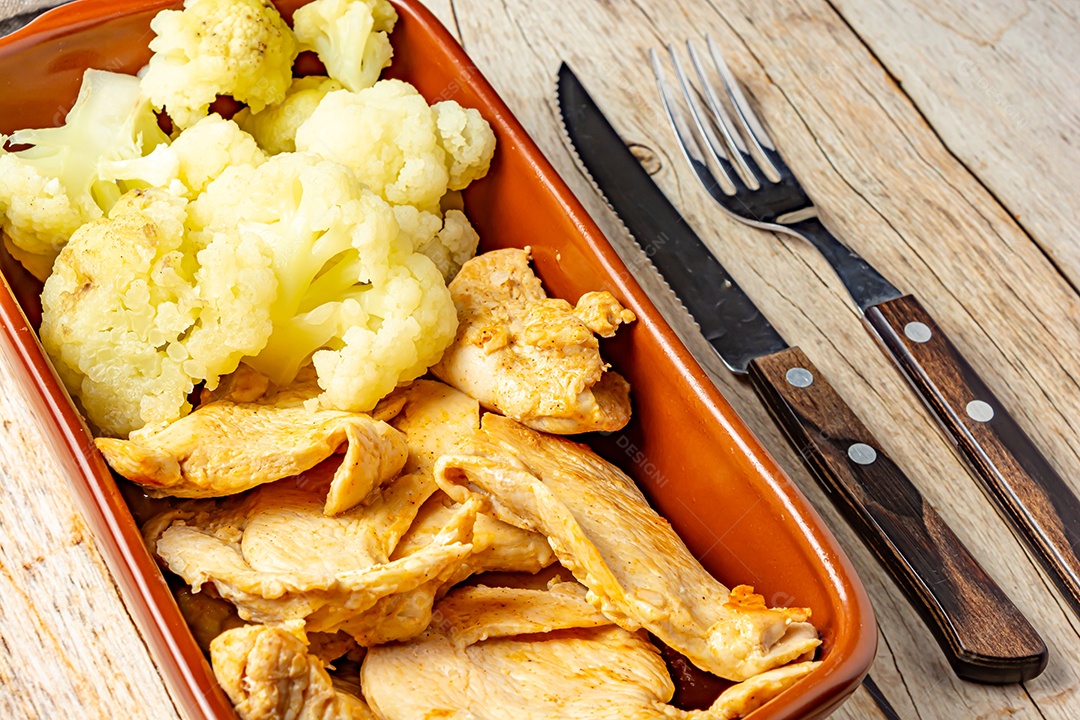 Refeição saudável, frango e couve-flor, em uma tigela sobre a mesa de madeira
