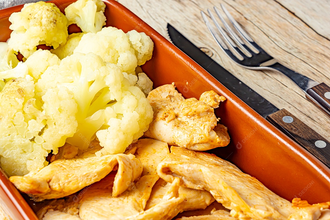 Refeição saudável, frango e couve-flor, em uma tigela sobre a mesa de madeira