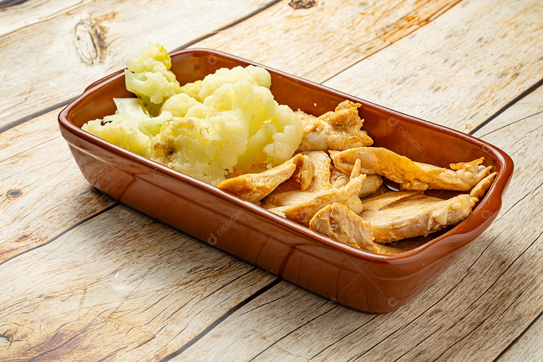 Refeição saudável, frango e couve-flor, em uma tigela sobre a mesa de madeira