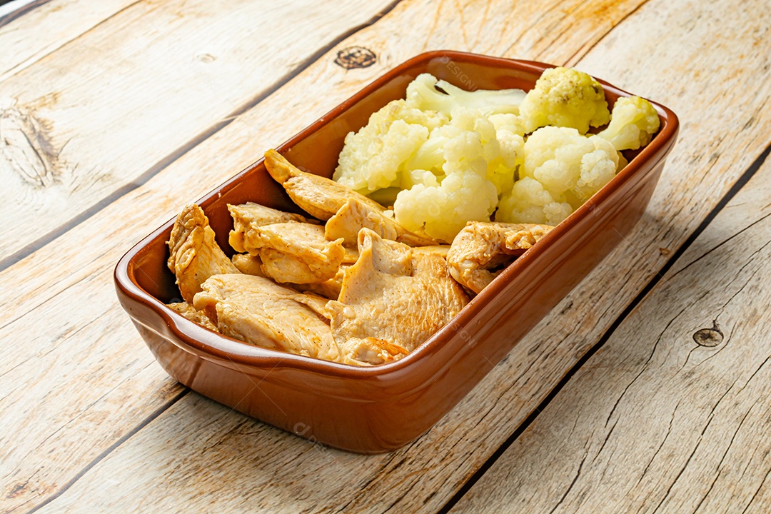 Refeição saudável, frango e couve-flor, em uma tigela sobre a mesa de madeira