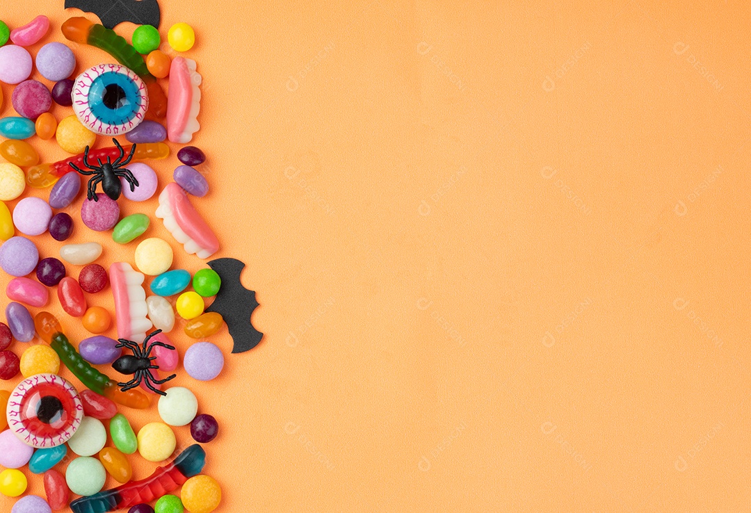 Doces coloridos sobre fundo laranja com espaço de cópia.