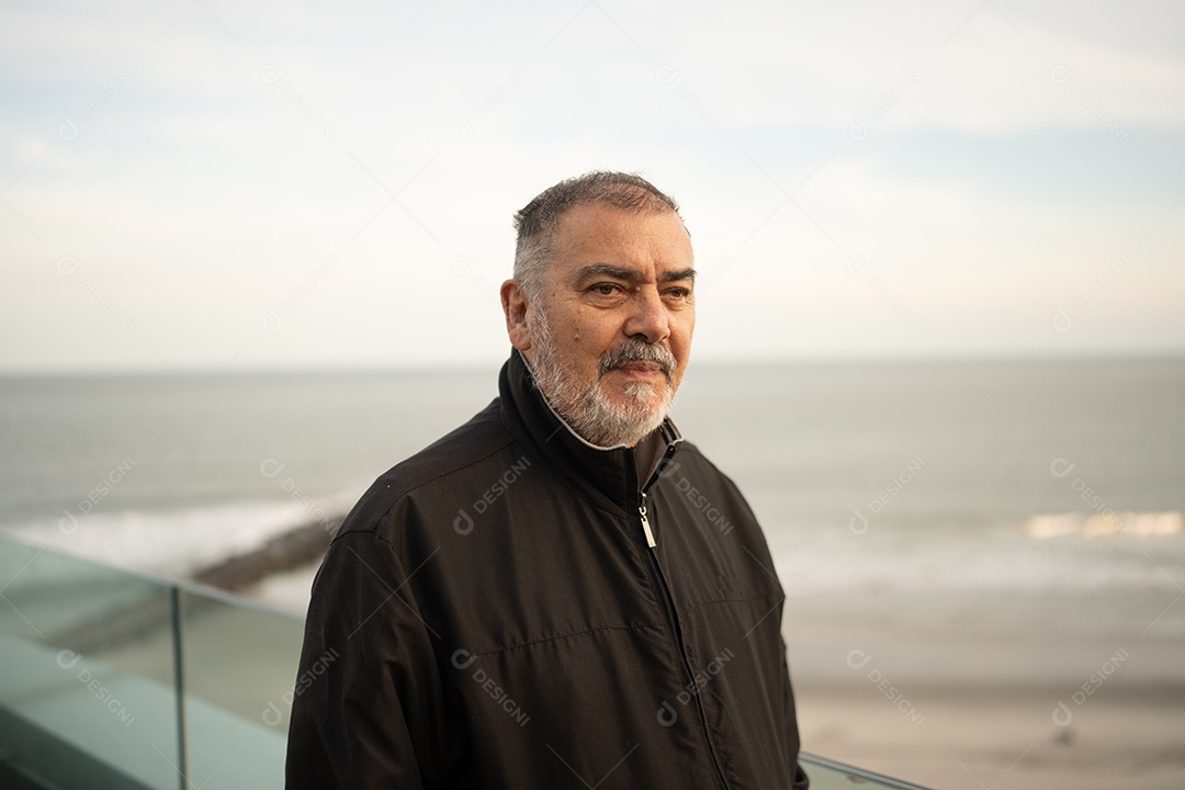 Um homem idoso com barba e cabelos grisalhos na praia.