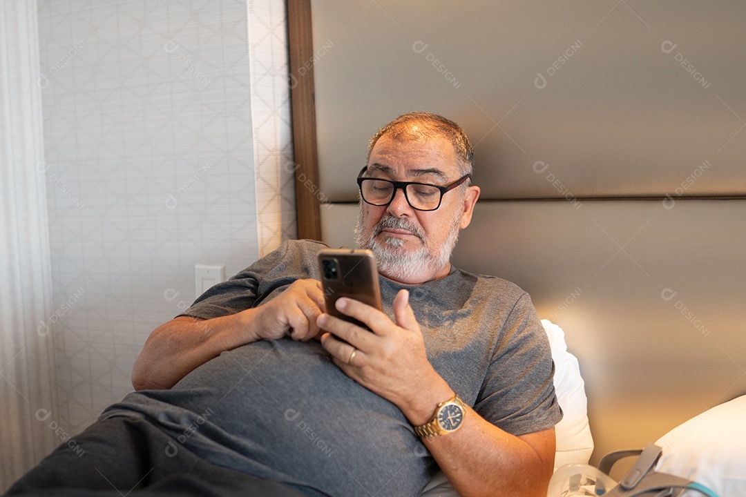 Um homem sênior feliz relaxando dentro de casa, sentado e usando óculos.