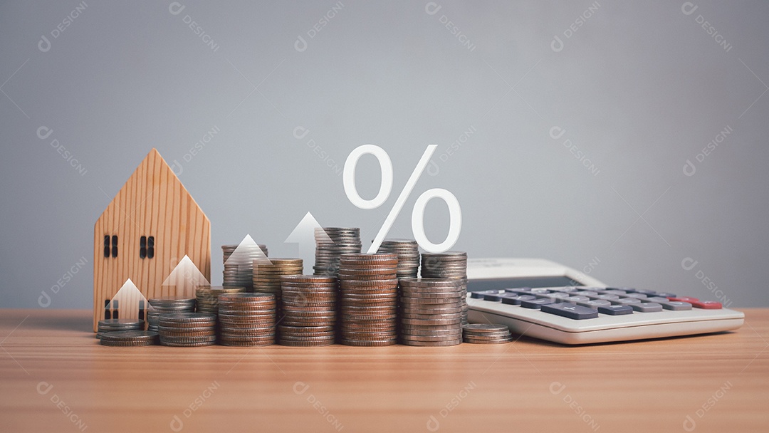 Modelo de casa de madeira, calculadora e moedas alinhadas no piso de madeira sobre fundo branco.